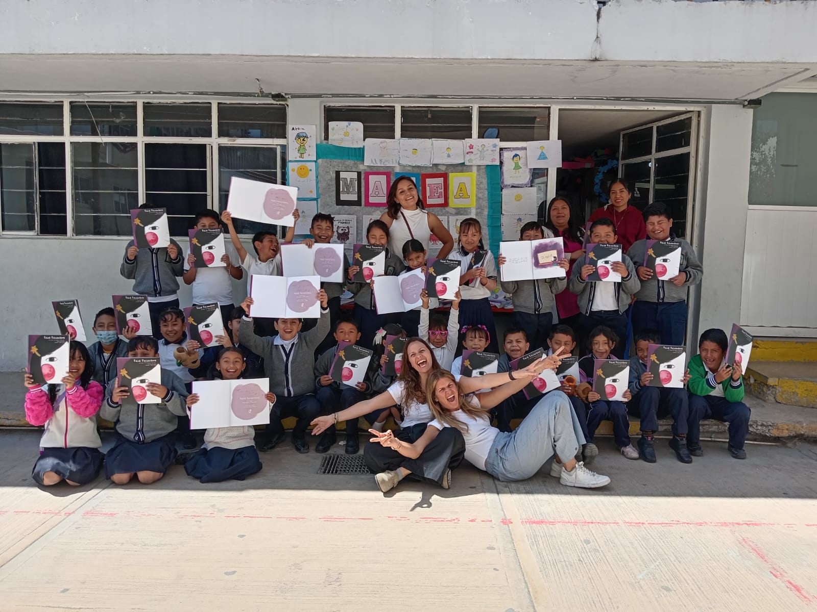 Niñas, niños y educadoras de la fundación con sus libros en el aula